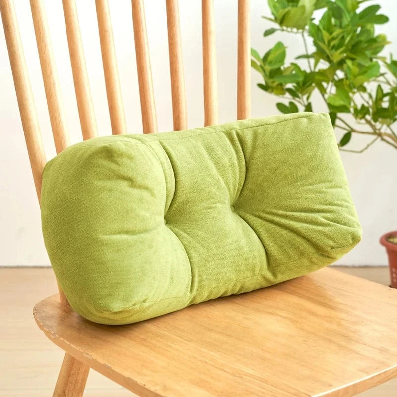 Coussin décoratif vert en velours, posé sur une chaise en bois, avec un design moelleux et des boutons décoratifs
