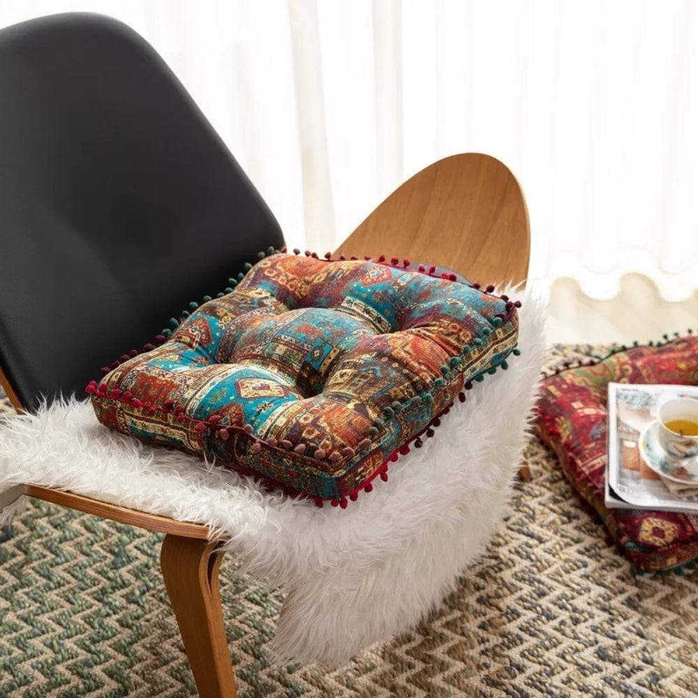 Coussin de sol coloré avec motifs orientaux, posé sur une chaise en bois, dans un coin lecture cosy