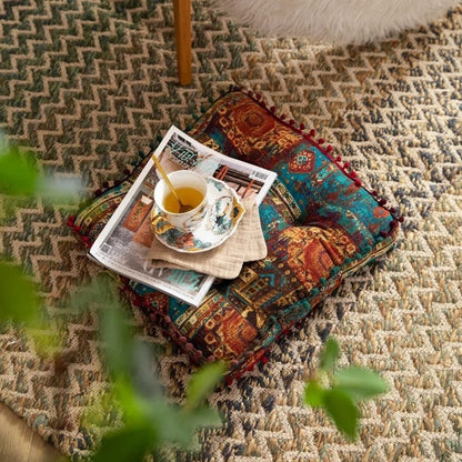Coussin de sol coloré avec motifs orientaux, posé sur un tapis en jute, avec une tasse de thé et un