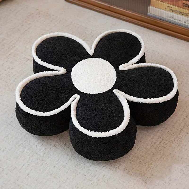 Coussin de sol en forme de fleur noir et blanc, posé sur un sol clair, ajoutant une touche décorative