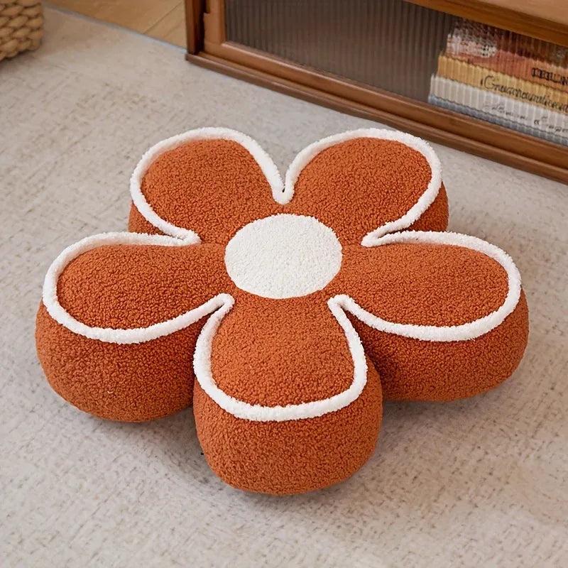 Coussin de sol en forme de fleur, couleur orange avec un centre blanc, sur un tapis neutre dans un salon