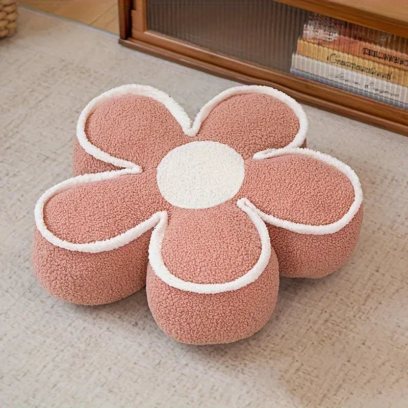 Coussin de sol en forme de fleur, couleur rose avec des contours blancs, posé sur un tapis doux