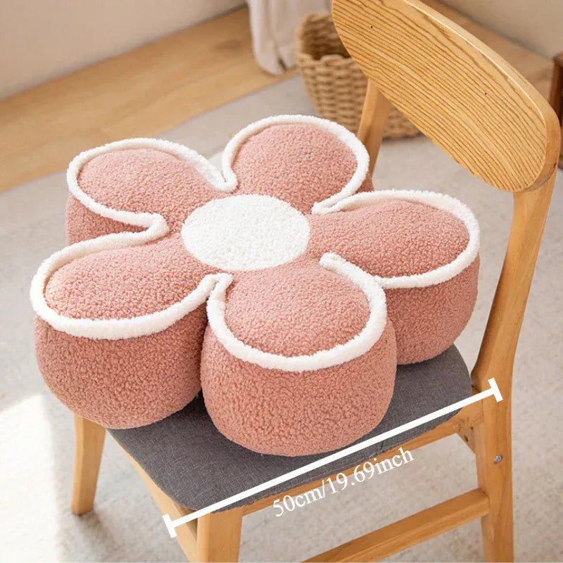 Coussin de sol en forme de fleur rose, avec des bords en peluche blanche, posé sur une chaise en bois