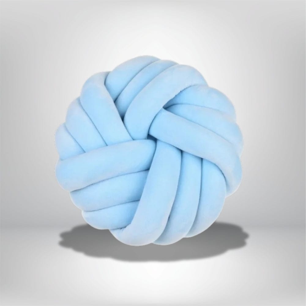 Coussin de sol en forme de nœud, en velours bleu clair, posé sur un fond neutre