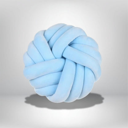 Coussin de sol en forme de nœud, en velours bleu clair, posé sur un fond neutre