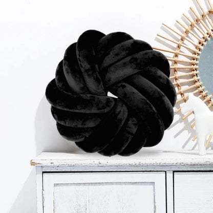 Coussin de sol noir en velours, en forme de nœud, posé sur une commode blanche dans un intérieur moderne