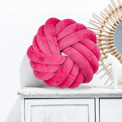 Coussin de sol en velours rose en forme de nœud, posé sur un meuble blanc avec un miroir décoratif