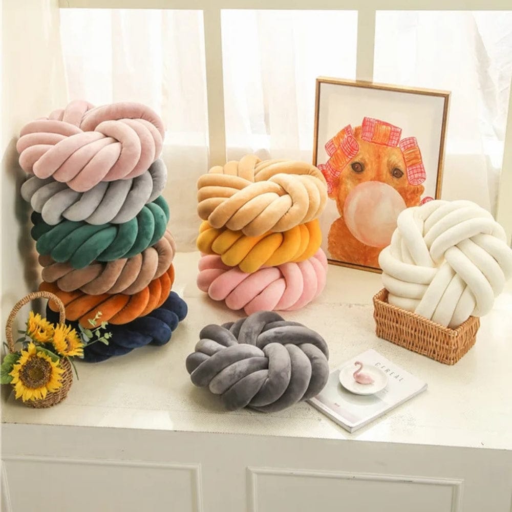 Coussins décoratifs en velours aux couleurs variées, posés sur une table avec un panier et un tableau