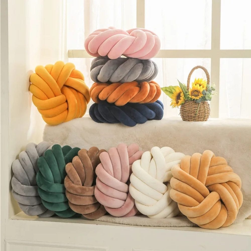 Coussins de sol en velours aux couleurs variées, disposés sur un canapé, créant une ambiance chaleureuse et décorative