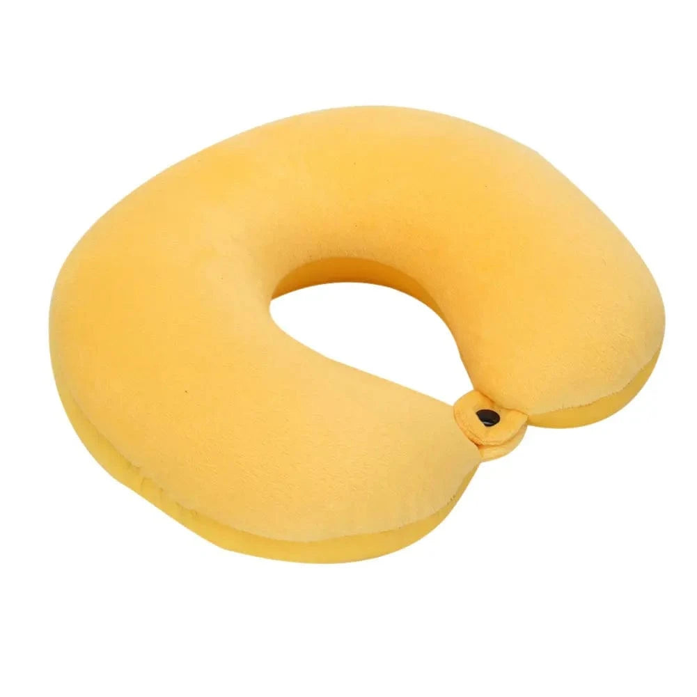 Coussin de voyage nuque en velours jaune, forme ergonomique, posé sur une surface plane