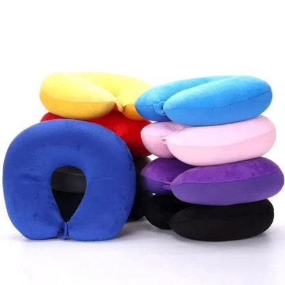 Coussins de voyage nuque colorés empilés, en velours doux, sur un fond neutre