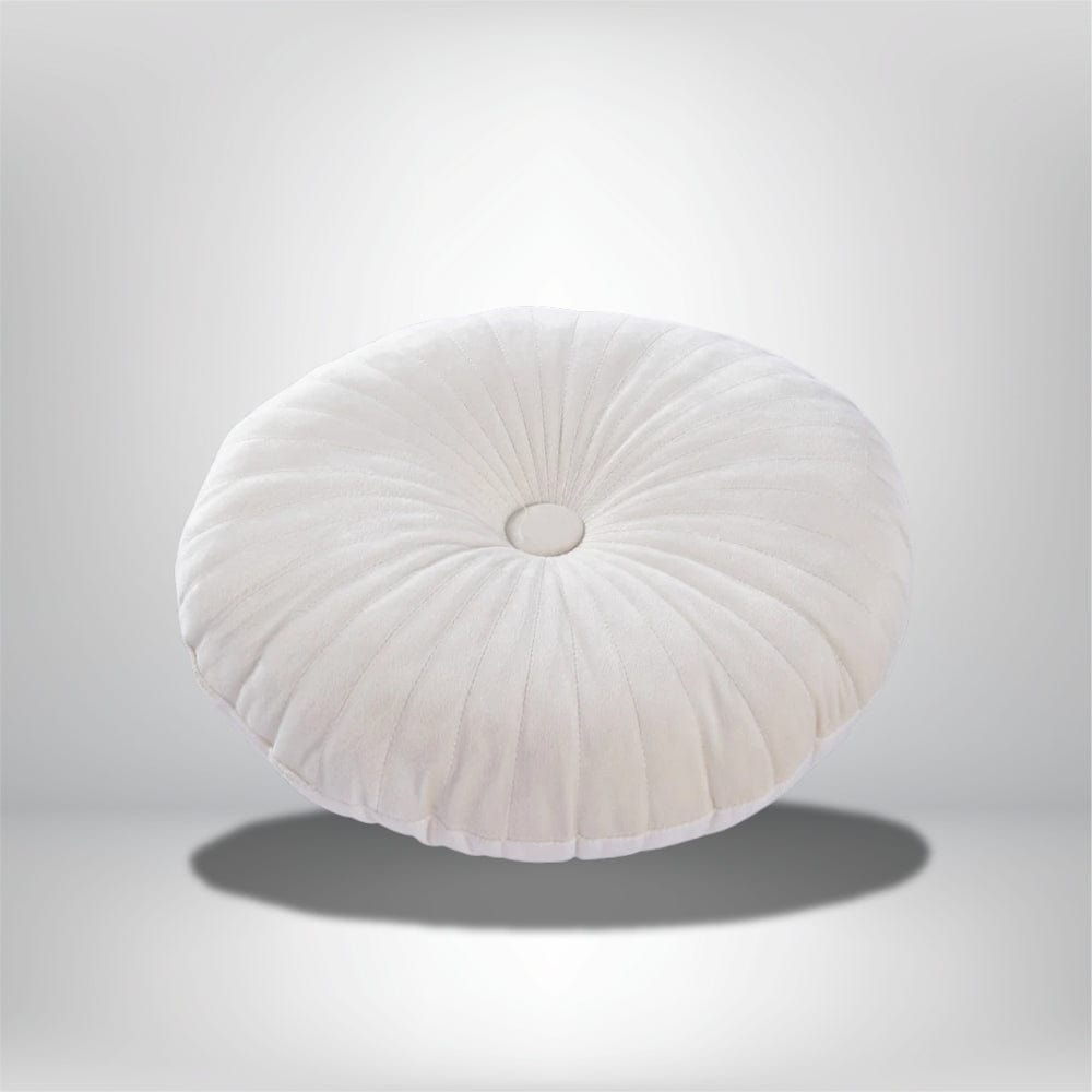Coussin déco rond en velours blanc, avec des plis et un bouton central, posé sur un fond neutre
