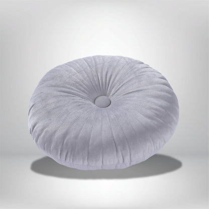 Coussin déco rond en velours gris clair avec des plis, posé sur un fond neutre