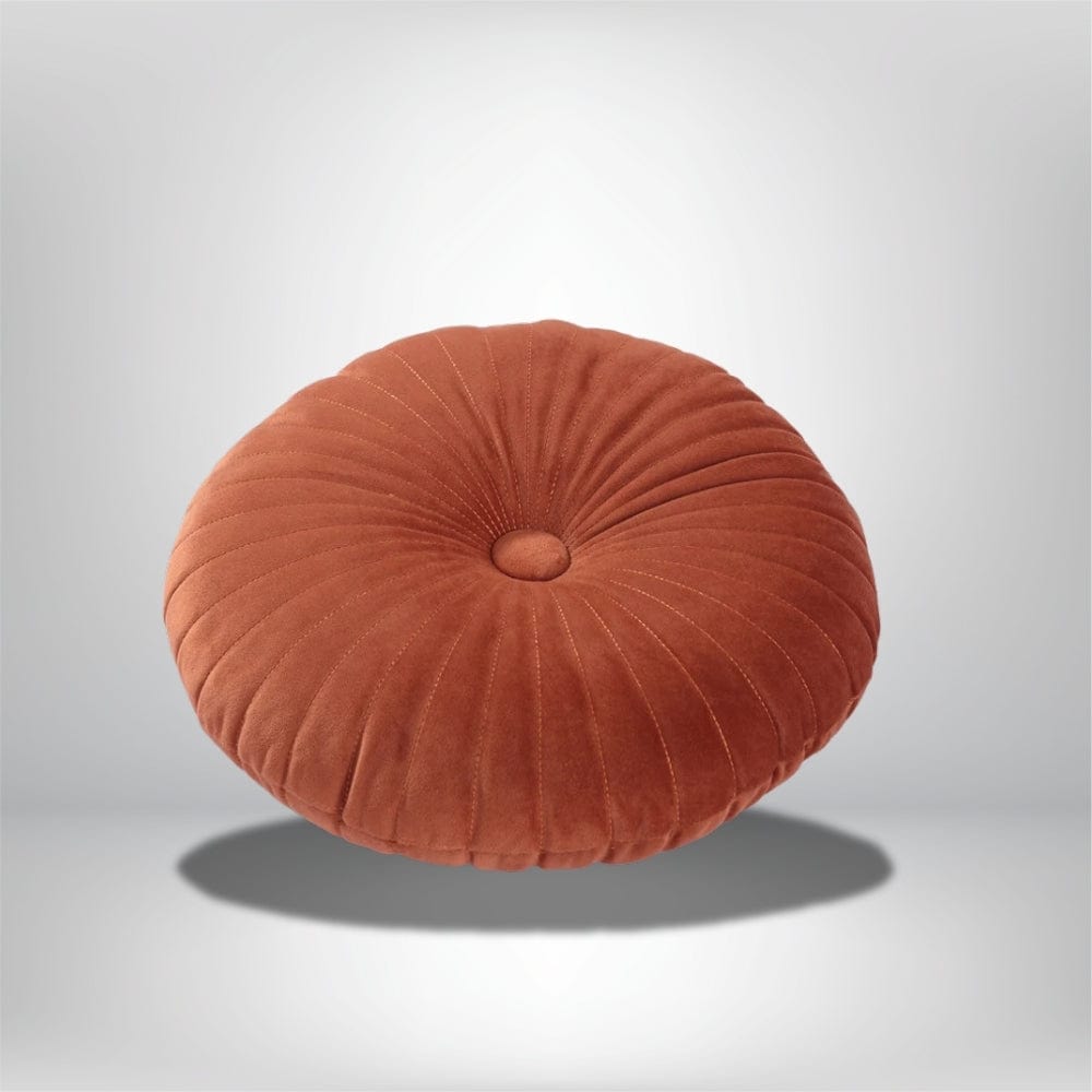 Coussin déco rond en velours orange avec des plis, posé sur un fond neutre
