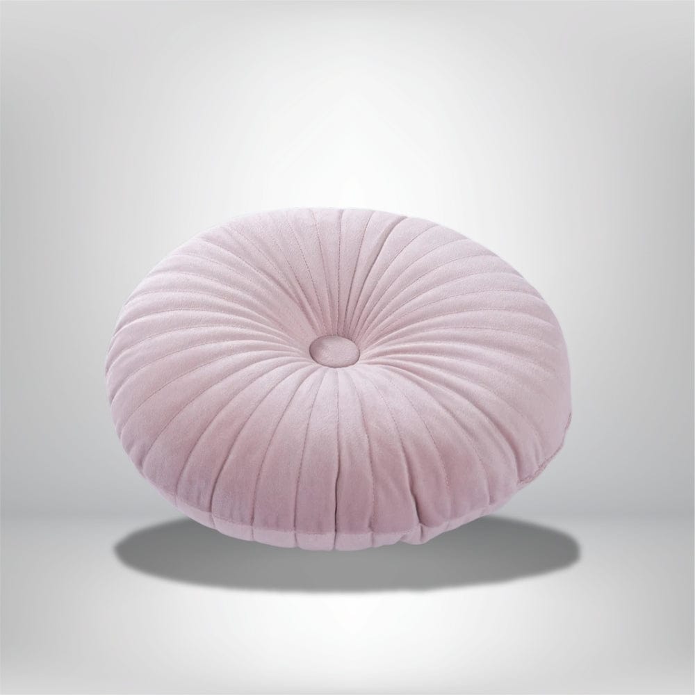 Coussin déco rond en velours rose avec des plis, posé sur un fond neutre, idéal pour un canapé