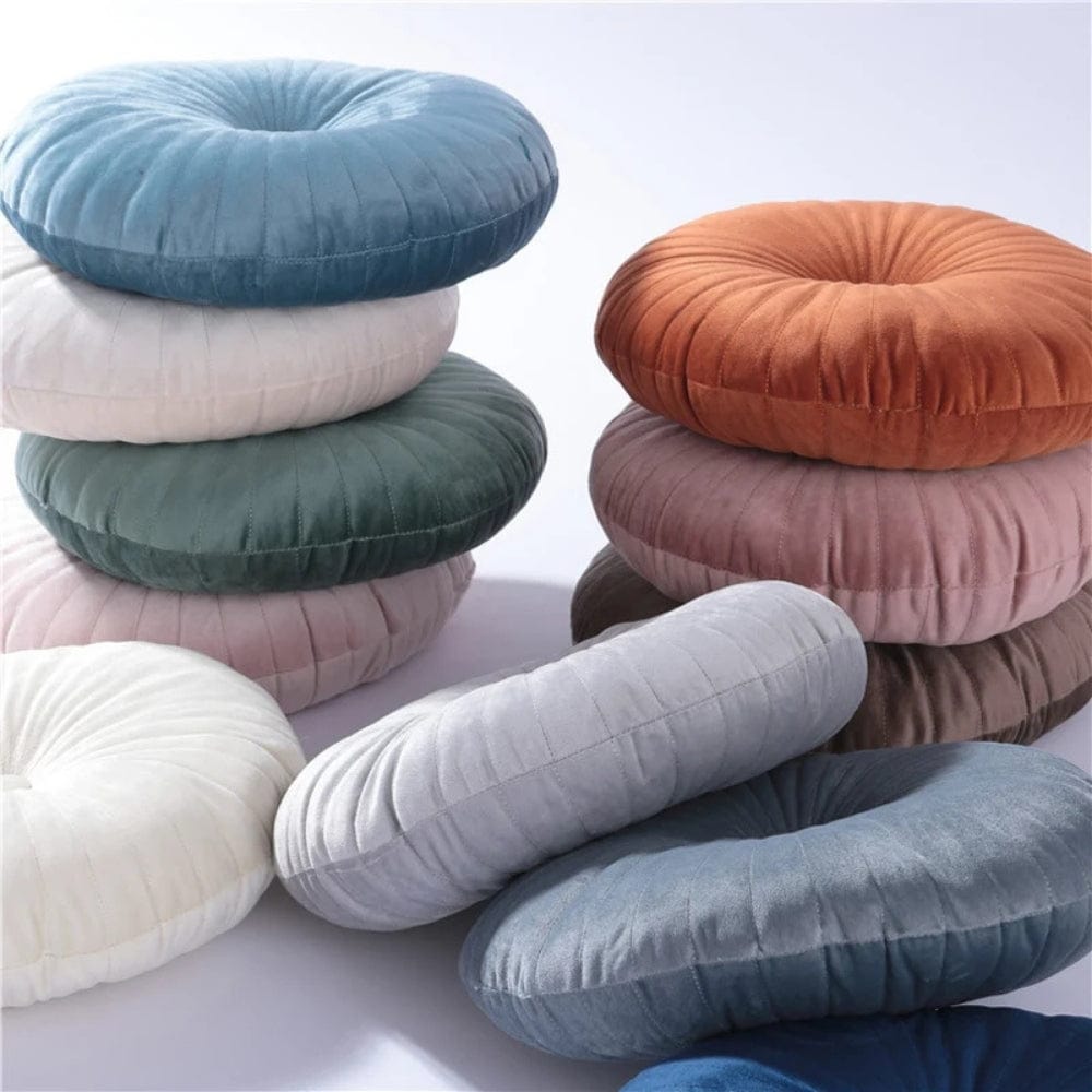 Coussins décoratifs ronds en velours aux couleurs variées, empilés sur un fond clair, parfaits pour un canapé