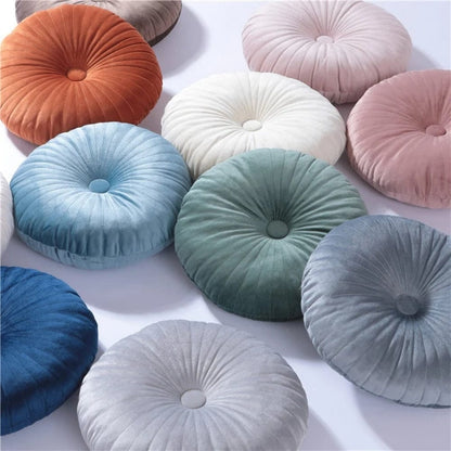 Coussins décoratifs ronds en velours aux couleurs variées, posés sur une surface blanche, parfaits pour un canapé