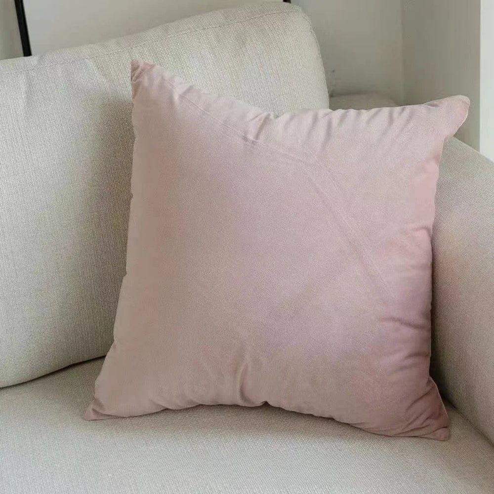 Coussin déco rose en velours posé sur un canapé beige, ajoutant une touche de douceur à l'intérieur