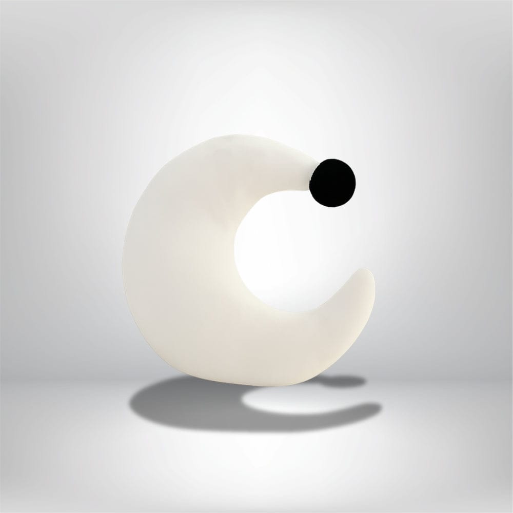 Coussin demi-lune blanc avec un point noir, idéal pour décorer un fauteuil moderne dans un salon