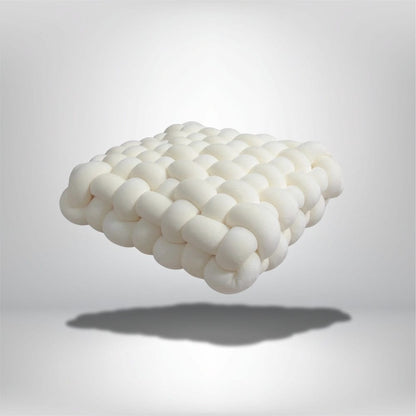 Coussin décoratif blanc en velours, au design moderne, posé sur un fond neutre, idéal pour un salon contemporain