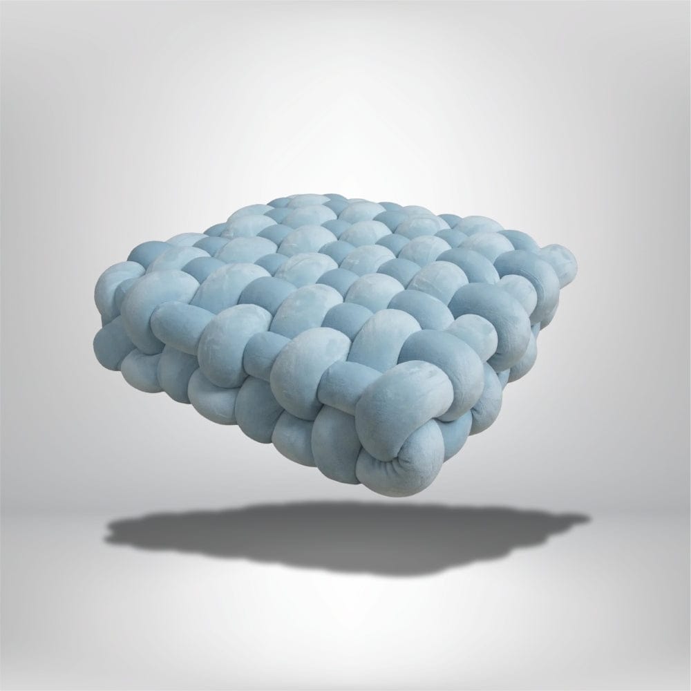 Coussin décoratif en velours bleu, forme moderne et originale, posé sur un fond neutre