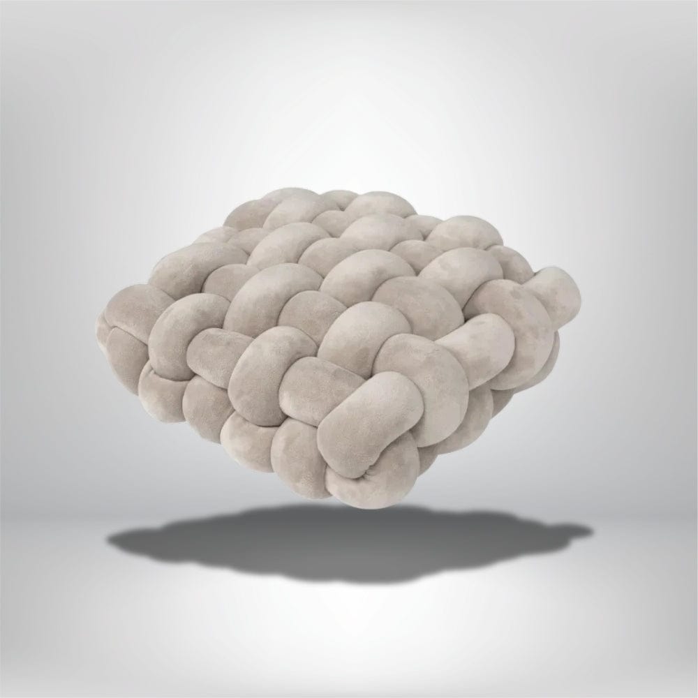 Coussin déco en velours beige, au design moderne, posé sur un fond neutre avec ombre douce