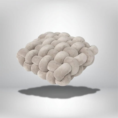 Coussin déco en velours beige, au design moderne, posé sur un fond neutre avec ombre douce