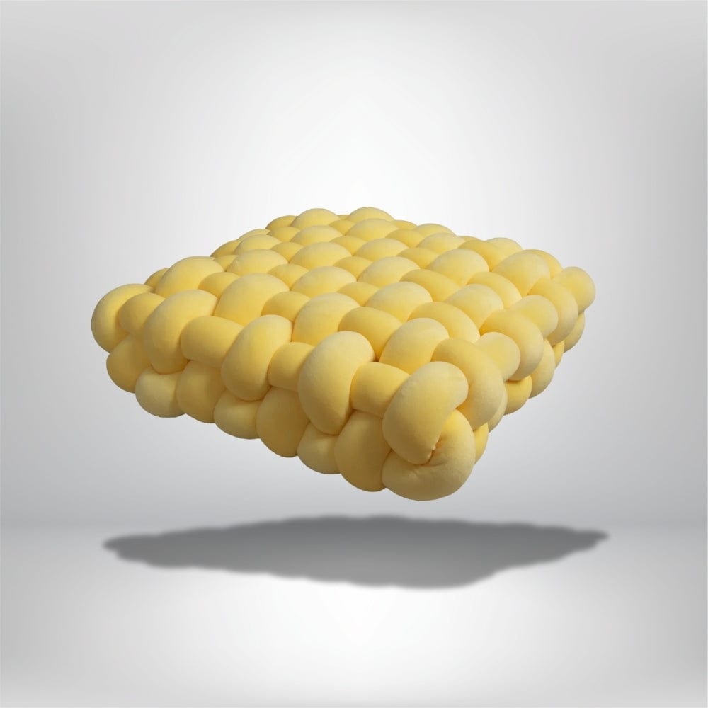 Coussin décoratif jaune en forme de carré, avec un design moderne et texturé, posé sur un fond neutre