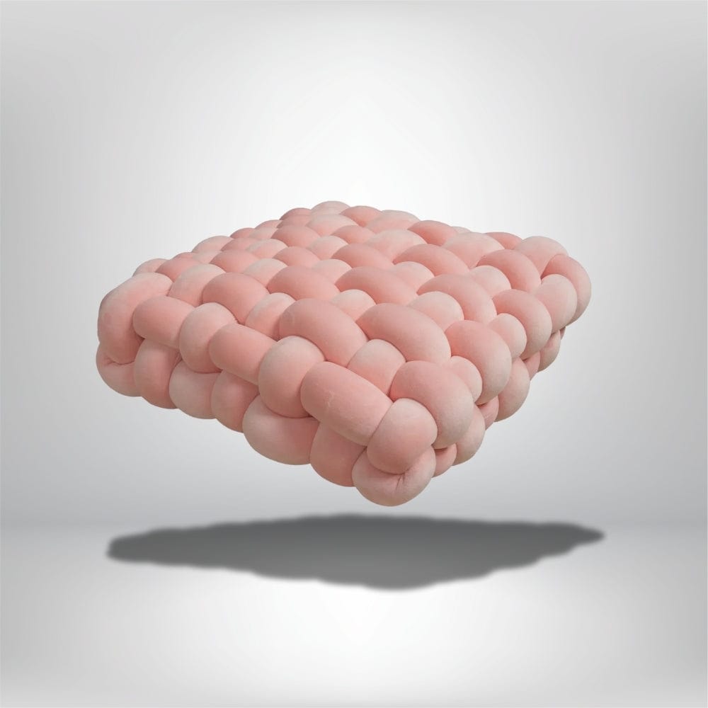 Coussin décoratif en forme de carré, en tissu rose avec un design moderne, posé sur un fond neutre