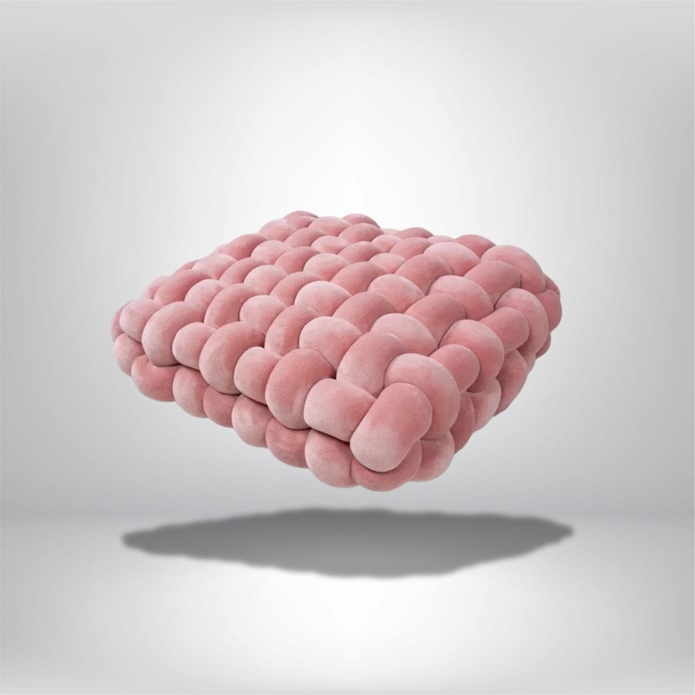 Coussin déco en velours rose, au design moderne et texturé, posé sur un fond neutre