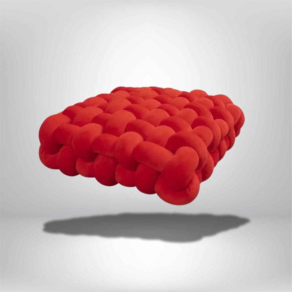 Coussin décoratif rouge en velours, au design moderne, posé sur un fond neutre, idéal pour un salon contemporain