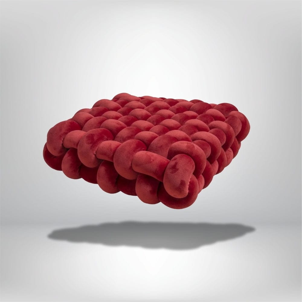 Coussin déco en velours rouge, au design moderne, posé sur un fond neutre, mettant en valeur sa texture unique