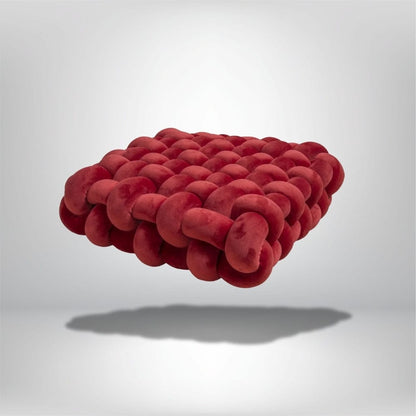 Coussin déco en velours rouge, au design moderne, posé sur un fond neutre, mettant en valeur sa texture unique