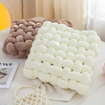 Coussins décoratifs en velours beige et blanc, tissés, posés sur une table avec un magazine et des accessoires