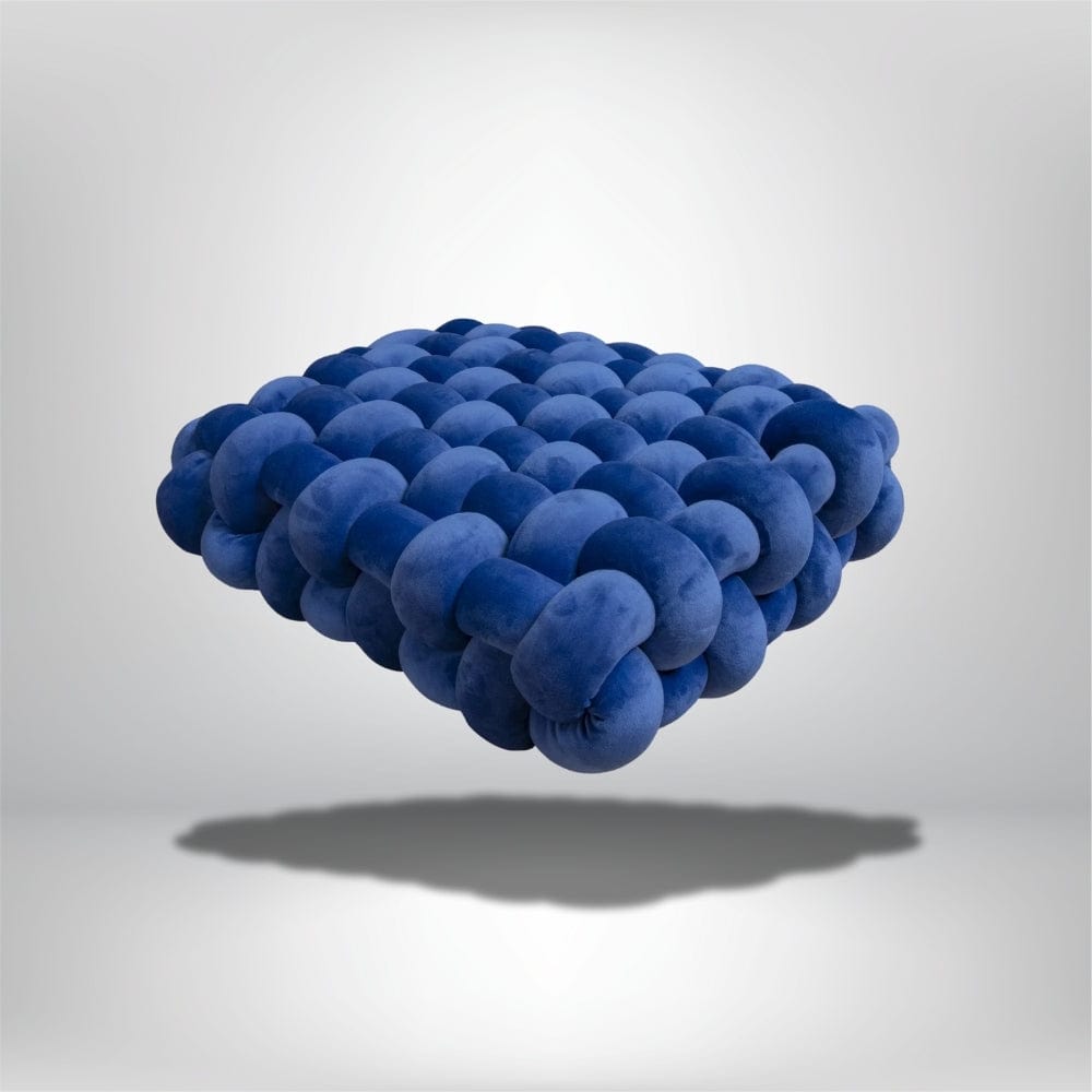 Coussin déco en velours bleu, forme moderne et texturée, posé sur un fond neutre