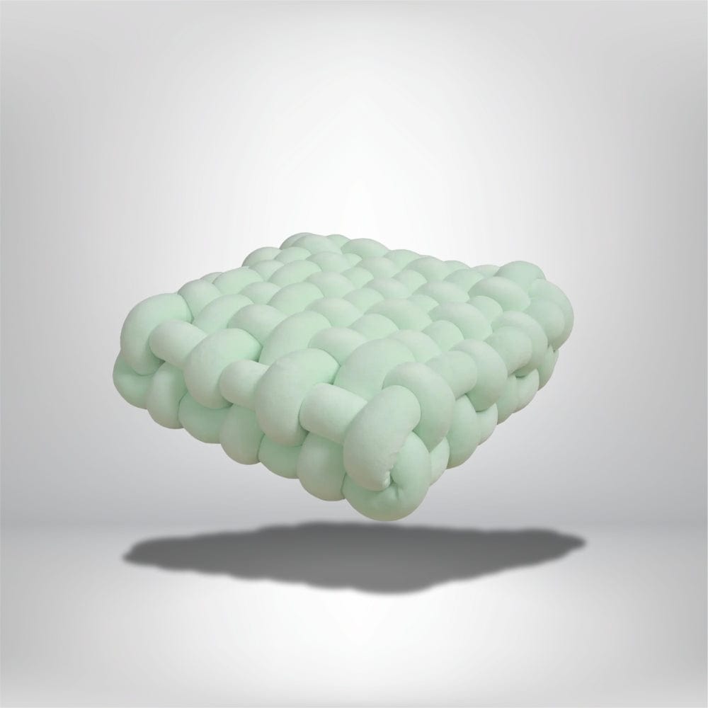 Coussin déco en forme de carré, couleur vert menthe, avec un design tressé moderne, posé sur un fond neutre