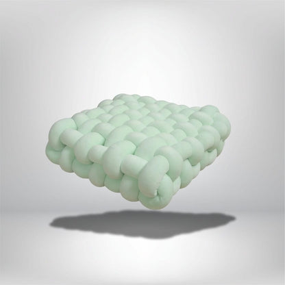 Coussin déco en forme de carré, couleur vert menthe, avec un design tressé moderne, posé sur un fond neutre
