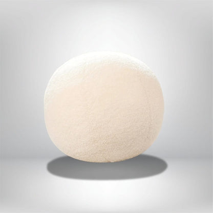 Coussin décoratif rond en tissu doux et pelucheux, couleur crème, posé sur un fond neutre