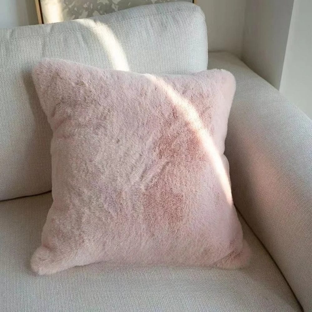 Coussin déco rose en matière douce, posé sur un canapé clair, ajoutant une touche chaleureuse au salon