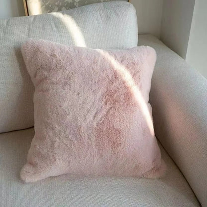 Coussin déco rose en matière douce, posé sur un canapé clair, ajoutant une touche chaleureuse au salon