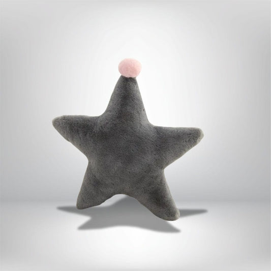 Coussin décoratif en forme d'étoile gris avec un pompon rose, posé sur un fond neutre