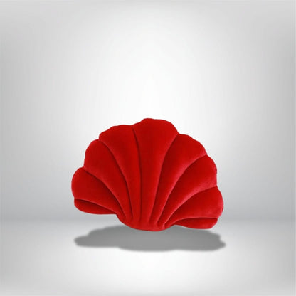 Coussin décoratif en velours rouge en forme de coquillage, posé sur un fond neutre