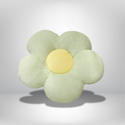 Coussin décoratif en forme de fleur, vert pastel avec un centre jaune, posé sur un fond neutre