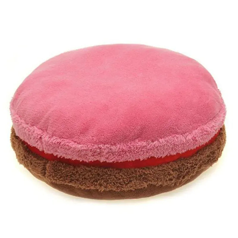 Coussin déco en forme de macaron, avec une surface rose douce et une base marron, posé sur un canapé