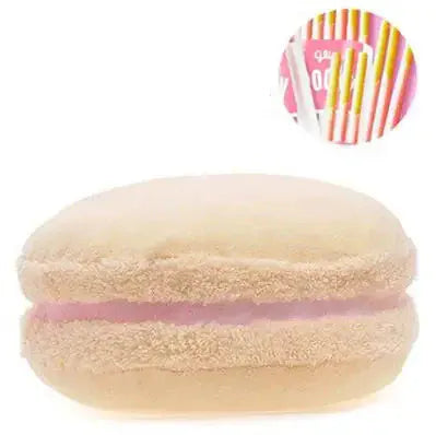 Coussin décoratif en forme de macaron, couleur beige avec une touche de rose, posé sur un canapé moderne