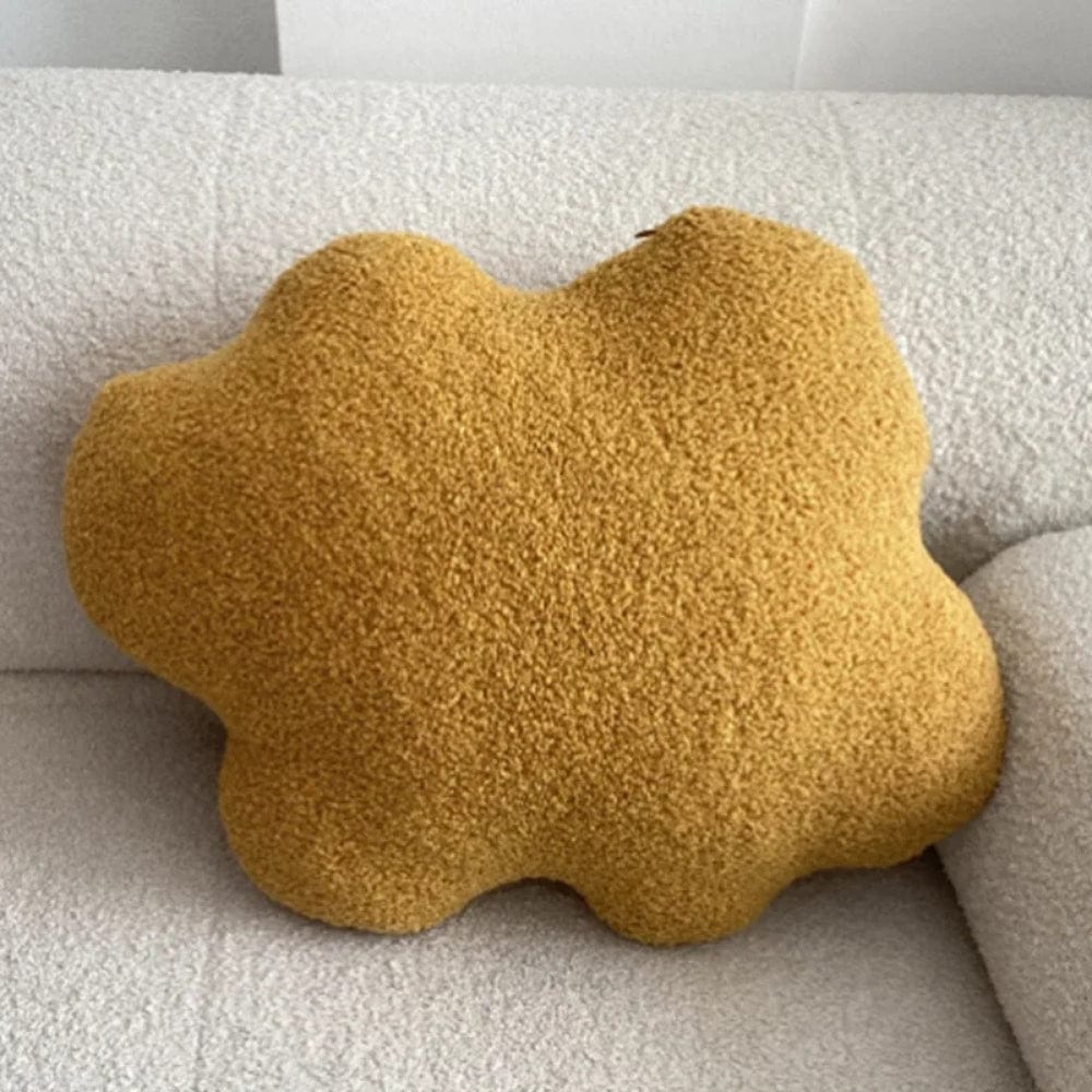 Coussin en forme de nuage de couleur jaune, posé sur un canapé en tissu beige texturé