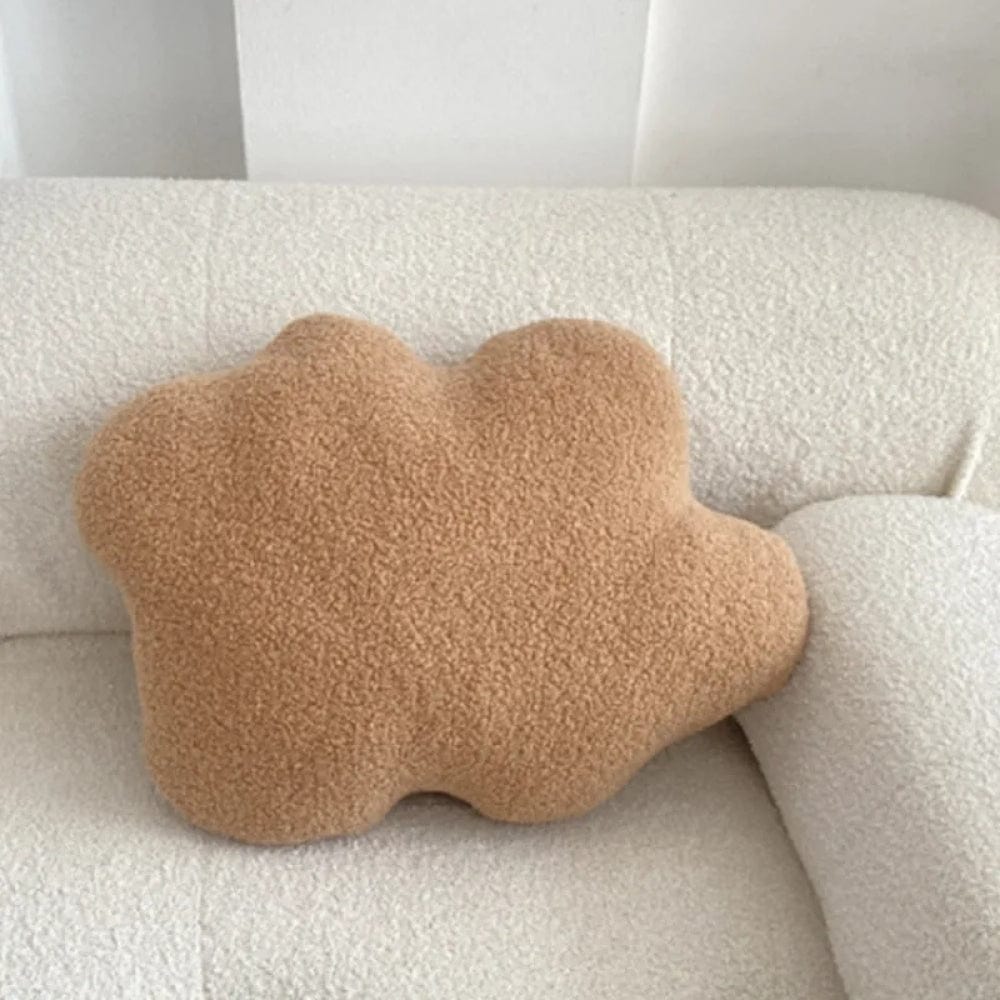 Coussin décoratif en forme de nuage, couleur beige, en matière douce, posé sur un canapé blanc