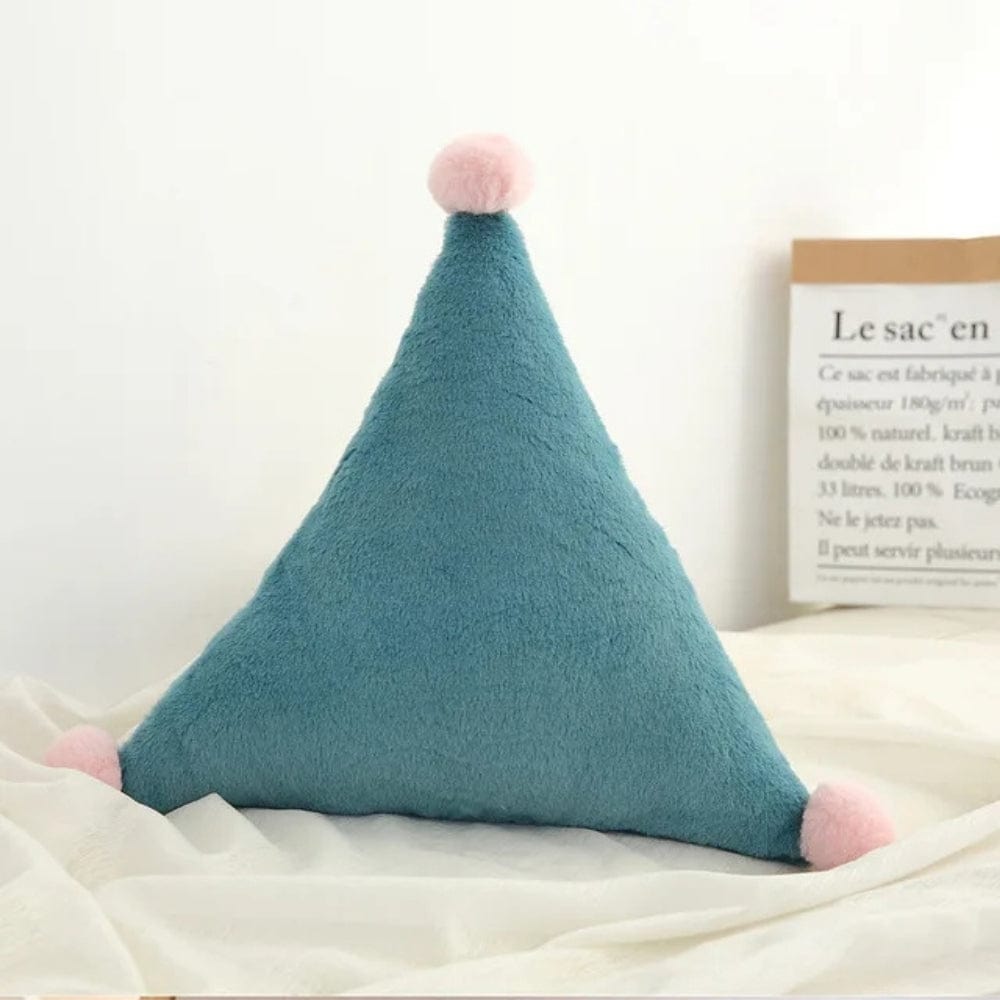 Coussin décoratif en forme de triangle, en velours bleu avec pompons roses, posé sur un tissu beige