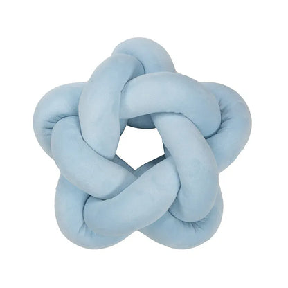 Coussin décoratif en forme d'étoile, en velours bleu, posé sur un canapé moderne dans un salon lumineux