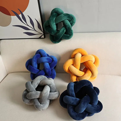 Coussins décoratifs en velours en forme d'étoile, disposés sur un canapé, dans des teintes variées de bleu, vert, jaune et